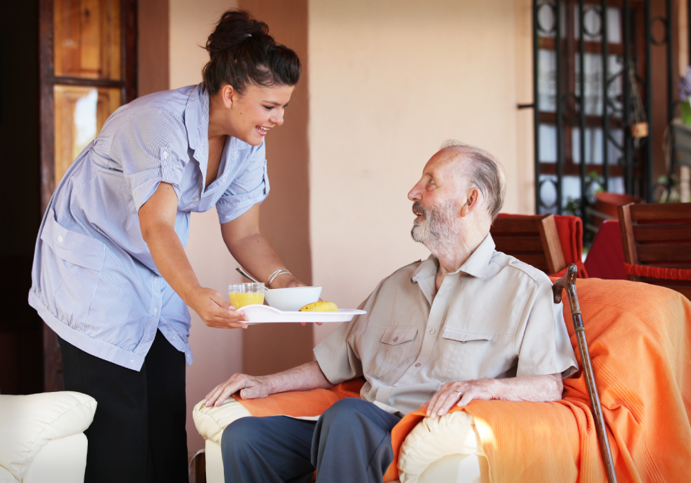 Caregiver Serving a Meal to an Elderly Man